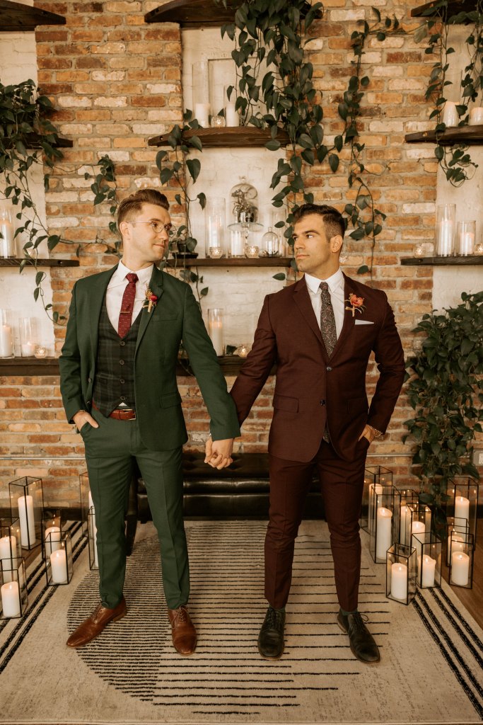 two grooms hold hands in suits